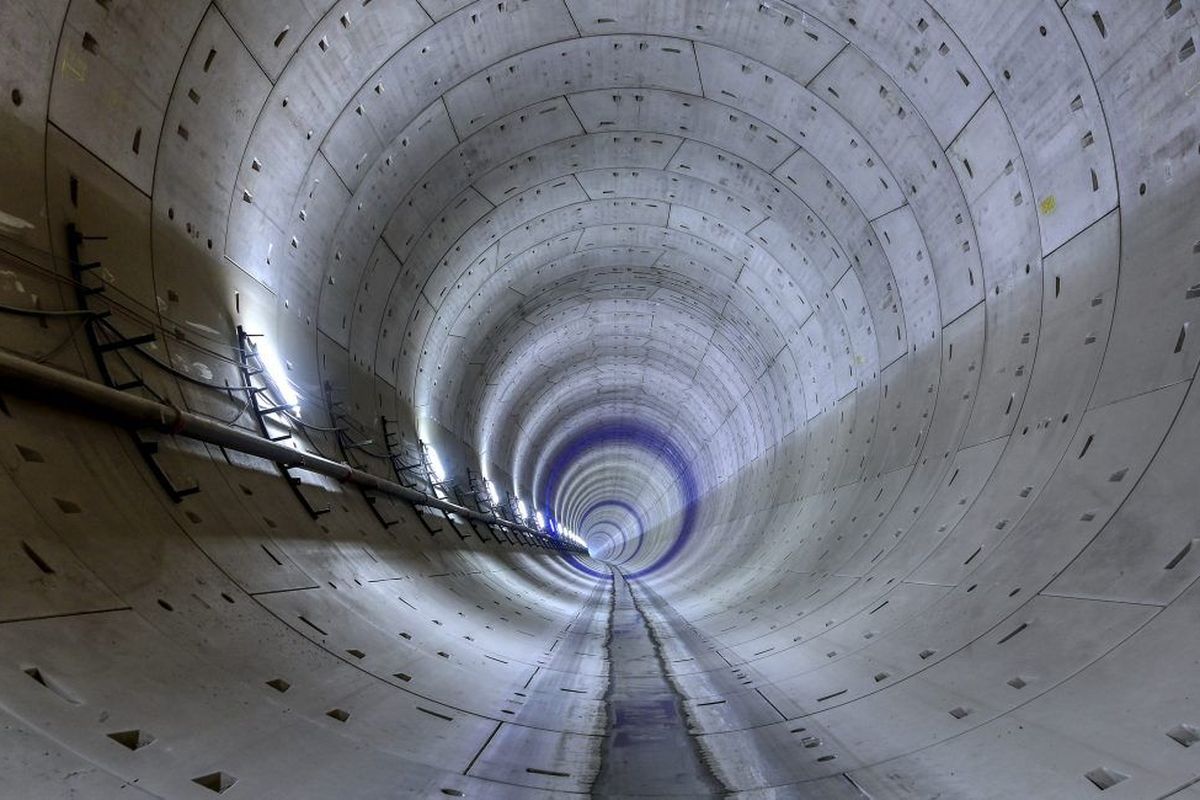 Ein Blick in einen langen, zylindrischen Tunnel mit Betonwänden und schwachem Licht am Ende.