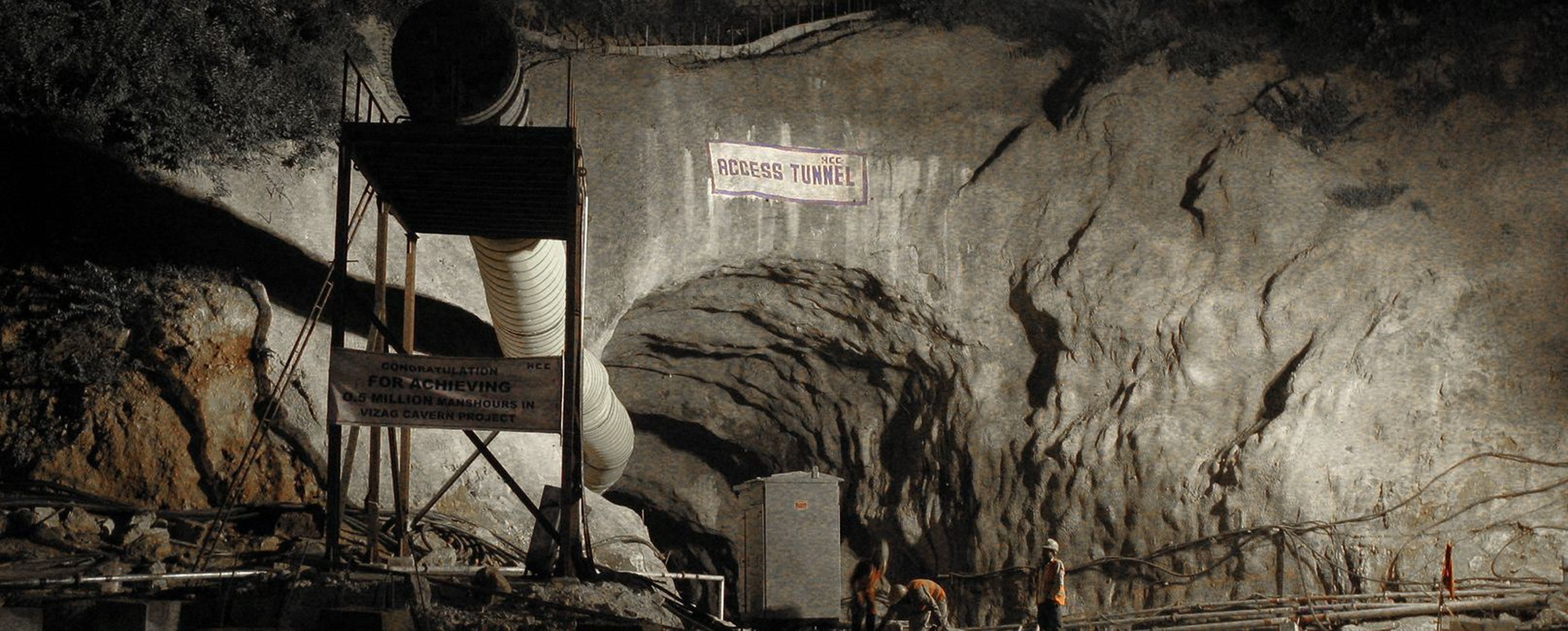Ein Tunnelportal mit einem Schild „Access Tunnel“ und Bauarbeiten im Inneren, beleuchtet von schwachem Licht.