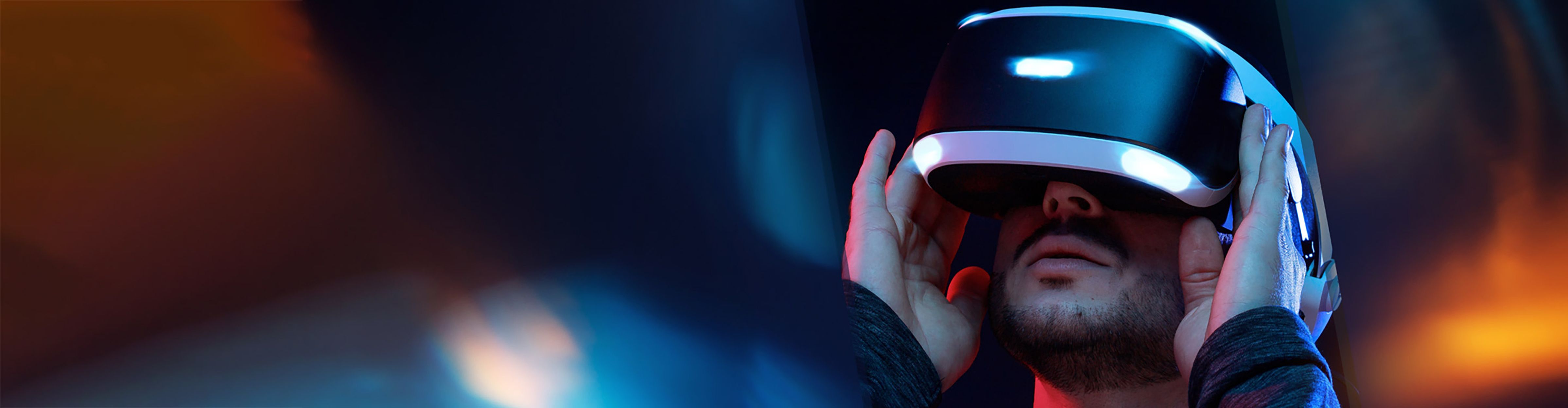 Eine Person trägt ein Virtual-Reality-Headset und interagiert mit der digitalen Umgebung in einem farbenfrohen Licht.