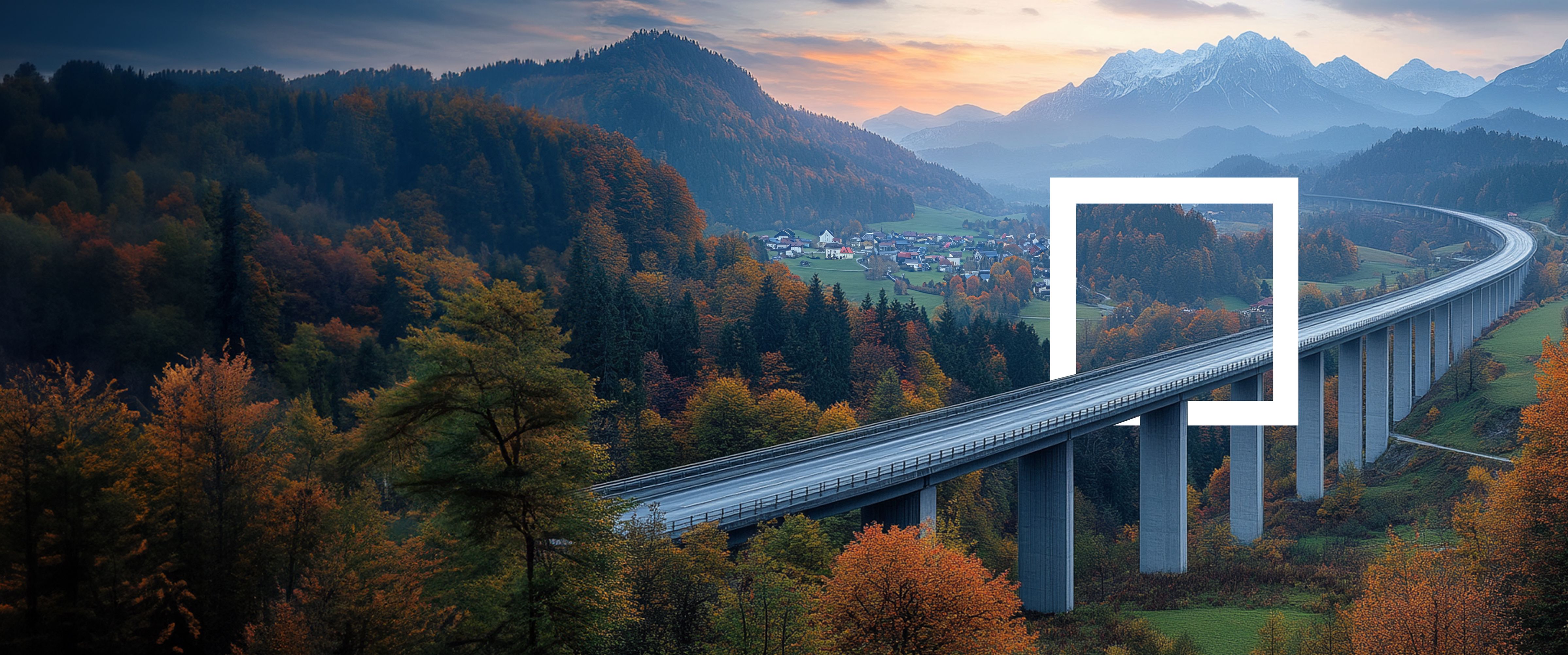A winding highway bridge stretches through a forested valley with autumn foliage, mountains, and a sunset sky in the background.