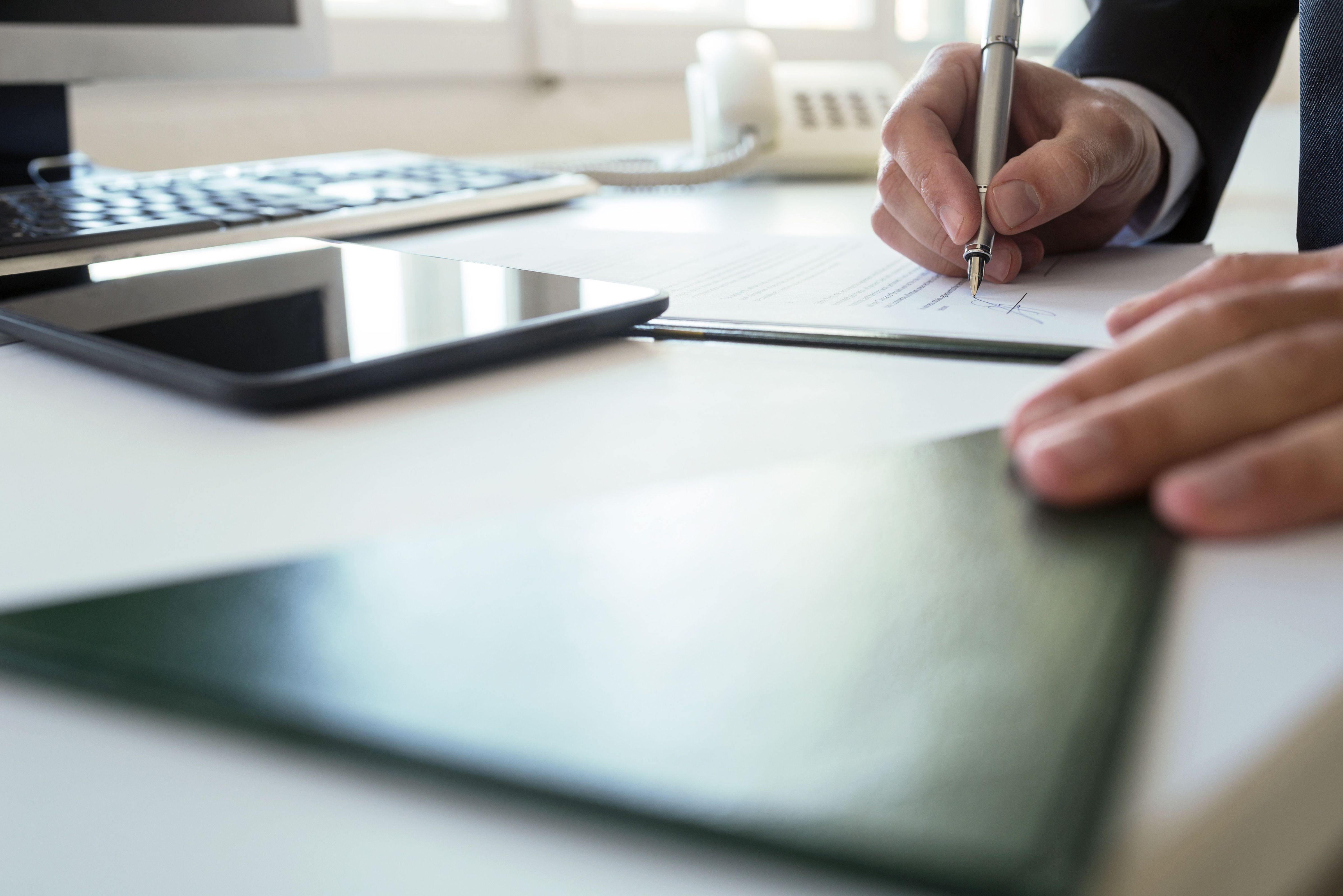 Geschäftsmann beim Unterzeichnen eines Dokuments an seinem Bürotisch